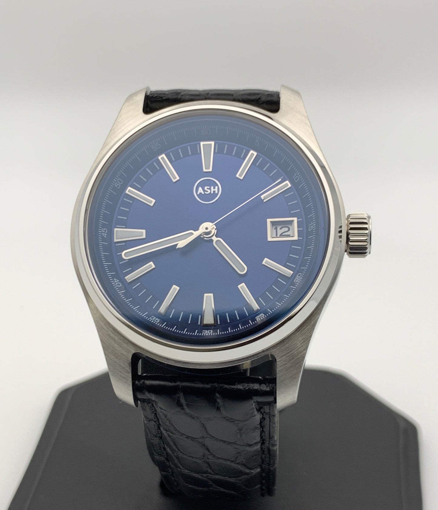 A blue sunburst dial wristwatch with a stainless steel case and black alligator leather strap, featuring a date display and screw down case-back.
