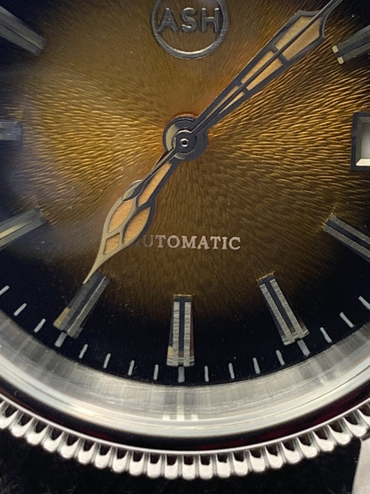 Homesick. 39mm Coin edged stainless steel case. Tobacco sunburst figured dial. AR coated domed mineral glass crystal. Seiko NH35 automatic movement.